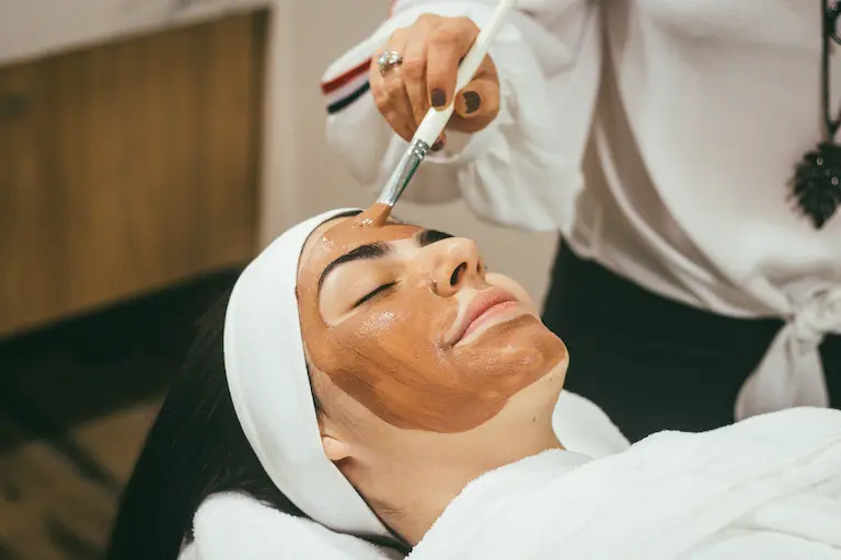 Cliente recibiendo tratamiento facial en clínica estética con servicios presentados en su página web profesional