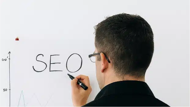 Hombre escribiendo SEO en una pizarra, representando los servicios SEO y el crecimiento continuo ofrecidos por SenshiCode.